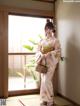 A woman in a kimono standing in front of a window.