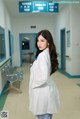 A woman in a white lab coat standing in a hospital hallway.