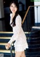 A woman in a white dress standing on a set of stairs.