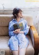 A woman sitting on a couch reading a book.