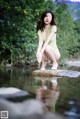 A woman sitting on a rock in the middle of a river.