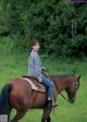 A woman riding on the back of a brown horse.