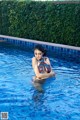 A woman in a bikini sitting in a swimming pool.